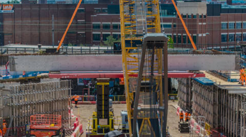 The beam is off the ground in the middle of the photo, going from left to right. A building is in the background on the right.