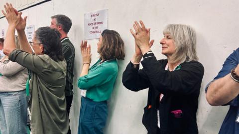 Crowds clap at an election count