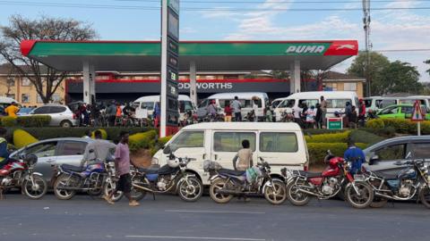 A wide view of a petrol station jammed with cars. Vehicles can also be seen on the road in front - all waiting to enter.