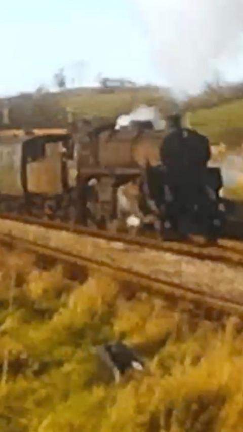 A still from an old, low-resolution film showing a steam train 