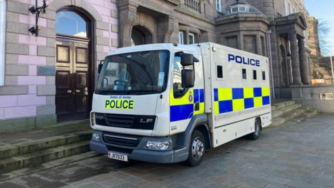 States of Jersey Police custody truck outside a stone building