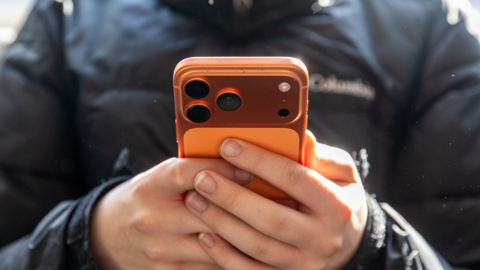 A young person using a orange mobile phone
