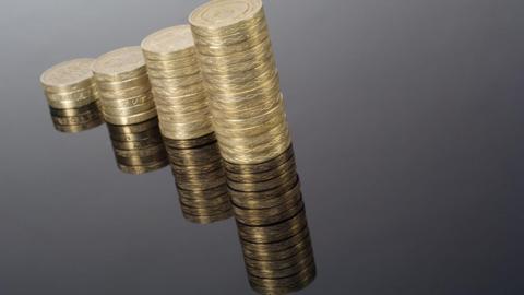 Pound coin graphic with columns on black - stock photo. The four piles of coins are stacked taller as you move from left to right. They are also reflected with a mirror effect in the bottom half of the picture. 