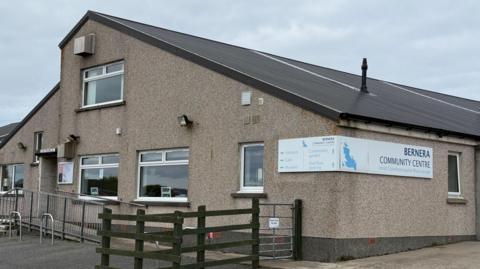 Togalach le ramp airson daoine cioramach agus feansa fiodha a-muigh. Tha soidhne air a' bhalla air a bheil Bernera Community Centre. 