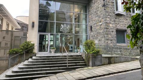 Outside of Guernsey's court building with steps leading up to a revolving glass door