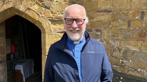 Rev Mike Barnsley stands outside the church, smiling