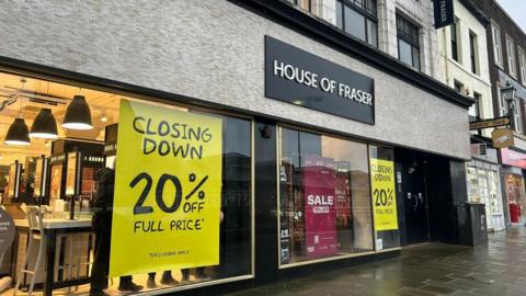 House of Fraser on High Row in Darlington. Large yellow signs advertising a 20% discount on items have been hung in the windows.