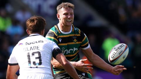 Northampton's Fraser Dingwall, faced by Henry Slade of Exeter, passes the ball to a team-mate