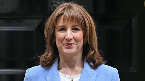 Head and shoulders shot of Rachel Reeves wearing a blue jacket, white shirt and gold necklace