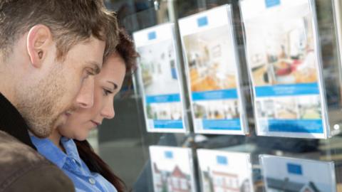 Man and woman look in estate agent's window 