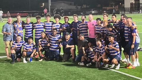 The Marshall Islands' first international team pose for a group shot after facing off the US Virgin Islands on Thursday in Springdale, Arkansas. They are at the pitch, looking away from the camera.