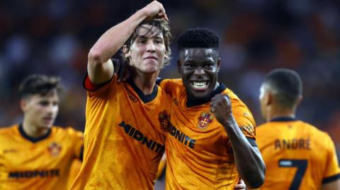 Fer Lopez and Marshall Munetsi, wearing Wolves' Old Gold home shirts, celebrate the first goal against Blackburn together by putting their arms around each other