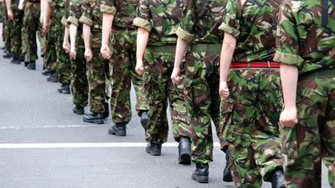 Close up shot of the legs of British soldiers who are in uniform and marching through the street
