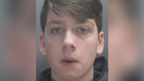 Custody image of Thomas Dures with brown hair and wearing a grey hoodie.