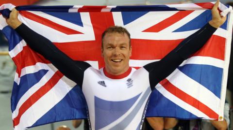 Sir Chris Hoy holding up British flag at Olympics