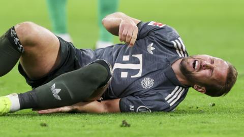 Harry Kane lies on the floor with his face clenched in pain after suffering an ankle injury against Bayer Leverkusen. 