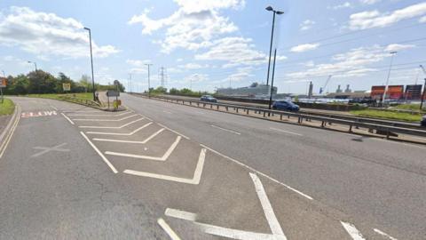Dual carriageway road with docks and cruise ship seen to the right.