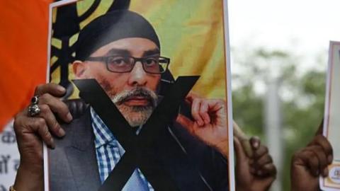 Photo of a man holding an image of Sikh separatist leader Gurpatwant Singh Pannun