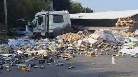 Been and pallets strewn across the motorway from a lorry which is on its side