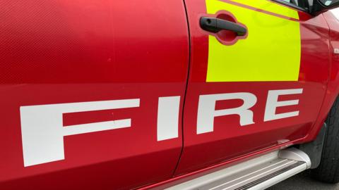 A close-up of the side of a red fire service vehicle.