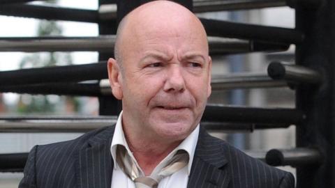 Liam Holden, pictured outside court before his death. He wears a pin stripe suit and a grey tie 