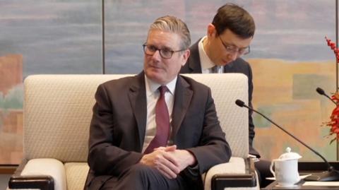 Sir Keir Starmer in a chair next to a microphone.