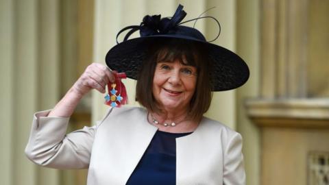 Julia Donaldson holding up a royal medal.