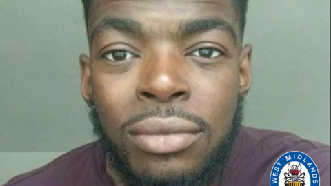 Joshua Johnson-Hector has dark eyes and a small moustache and beard. He is wearing a purple top