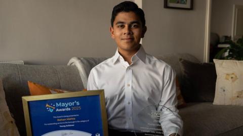 Rohan in his Kensington home holding two awards