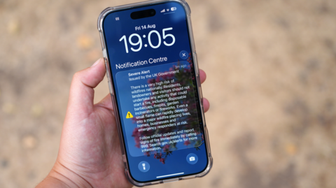 A mobile phone with a text message warning for the government which said there is a "very high risk of wildfires! and asked people not start a fire by setting off fireworks or lighting barbecues, fire pits or incinerators at home.