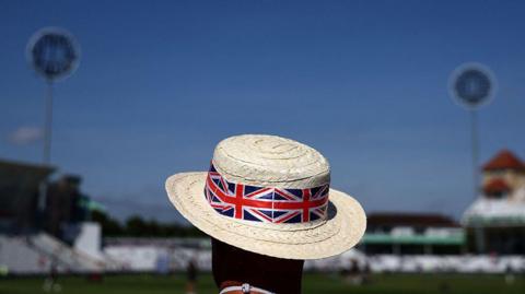 A man wearing a sun hat adorned with a Union Jack design watches on before a cricket match at Trent Bridge in Nottingham