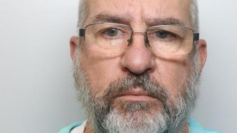A mugshot of Peter Woolner. He is wearing glasses and has a thick grey beard. 