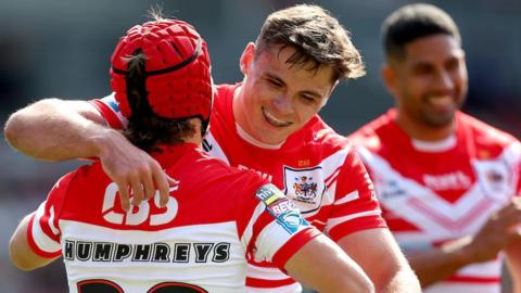 Jack Welsby puts his right arm around Tom Humphreys to congratulate the teenager on scoring his first try for St Helens.