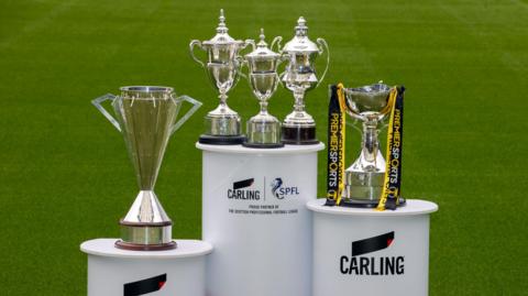 A number of Scottish football trophies, on podiums with the SPFL and Carling logos across them