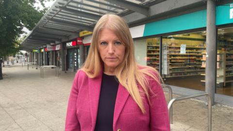 Donna jones wearing black and pink and stood in the high street