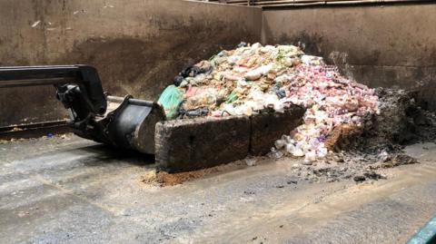 A mountain of food waste being moved by a large digger. 