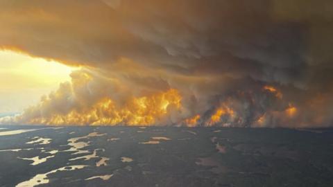 A handout photo made available by the government of Manitoba shows a large wildfire near Flin Flon, Manitoba, Canada. It shows woods and flames with large plumes of smoke filling the sky 