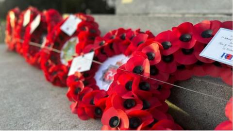 Wreaths made using red plastic poppies placed on grey concrete steps.