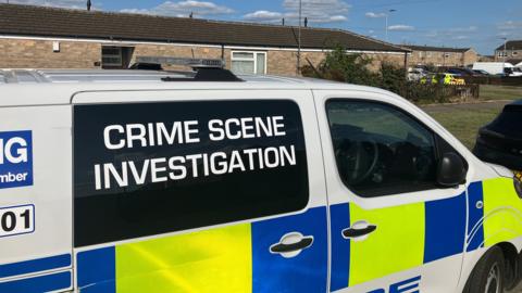 A police van parked in front of a property with Crime Scene Investigation written on it.