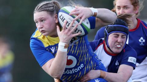 Alaw Pyrs of Gwalia Lightning is tackled by a Wolfhounds player