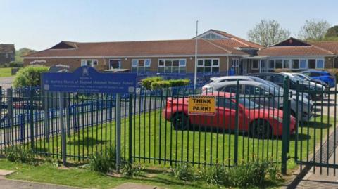 St Martin's Church of England School in Scarborough is a single storey building with the entrance fenced off with a large car park to the right of the image