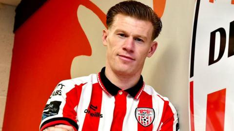 Shows a man with his hair brushed back in a red-white-and-black football jersey 