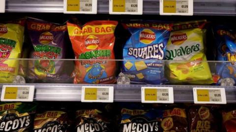 Packets of crisps on supermarket shelves offering a discount if you buy two packets, £1.25 for one but £1.95 for two