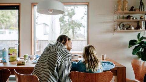 Rear view of a mother and daughter doing school work at a table