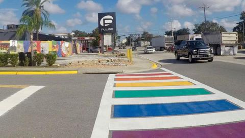 The rainbow crosswalk memorialising the victims of the Pulse nightclub shooting in 2016. The rest of the colourful memorial is visible in the background, as well as the nightclub's logo that reads 'Pulse'. 