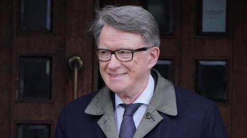 Peter Mandelson, dressed in a formal shirt, tie and outdoors jacket