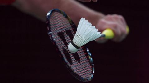 A detailed view of a racket and shuttlecock during a badminton service
