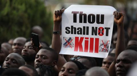 Christians faithfuls hold signs as they march on the streets of Abuja during a prayer and penance for peace and security in Nigeria in Abuja on March 1, 2020 - they are holding a sign that says 'thou shall not kill'