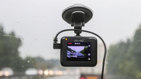 A black dashcam in a car recording