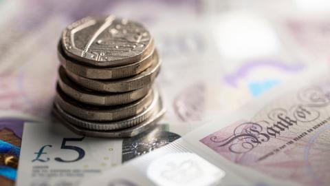 A stack of coins resting on a stack of bank notes.